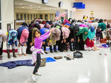 A young girls waves the American flag as Muslim women step away from the protests to take to...
