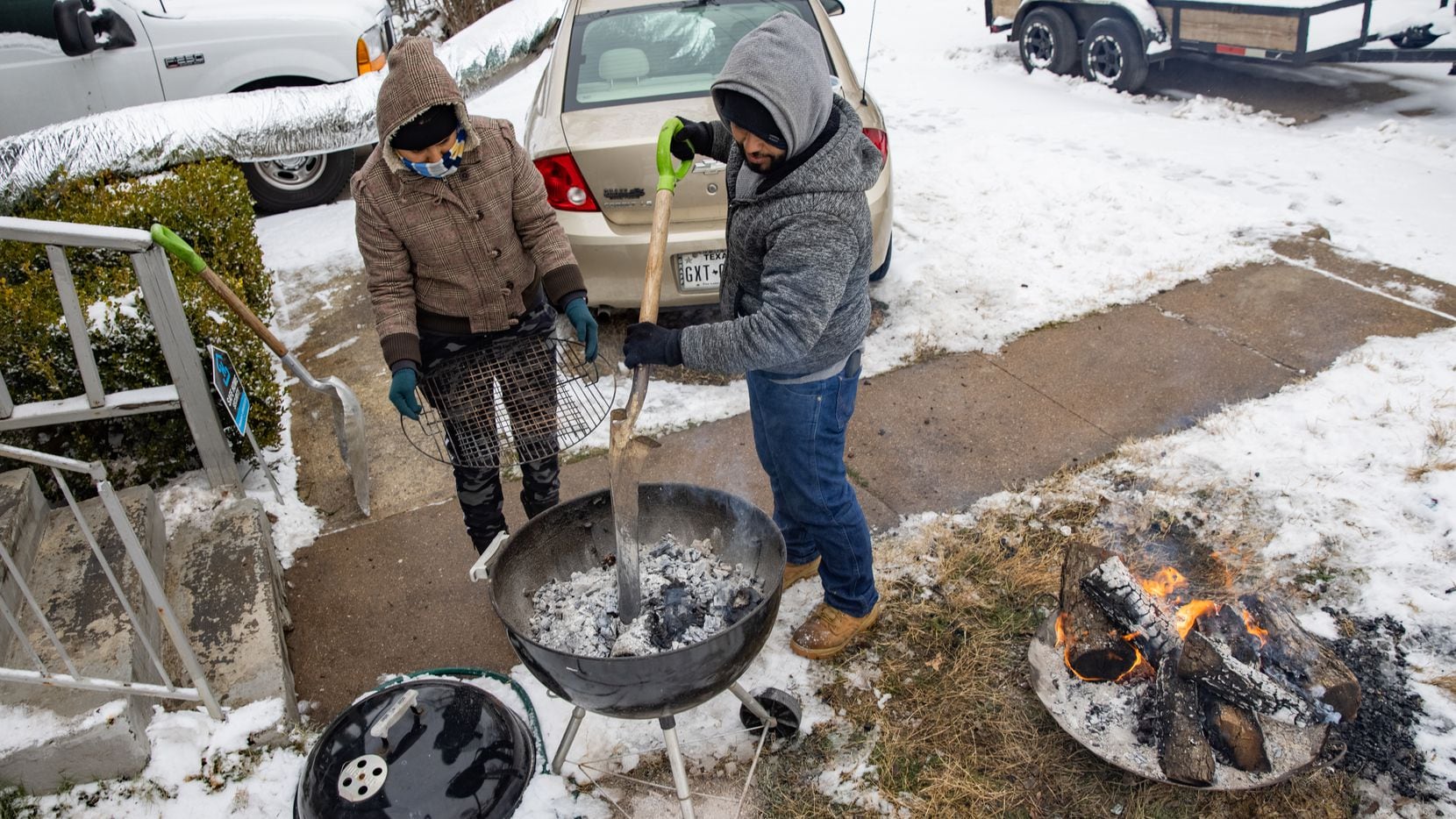 In Feb. 17 file photo, an East Dallas couple who'd lost power three days earlier and were staying warm in their car cook a meal on a grille.