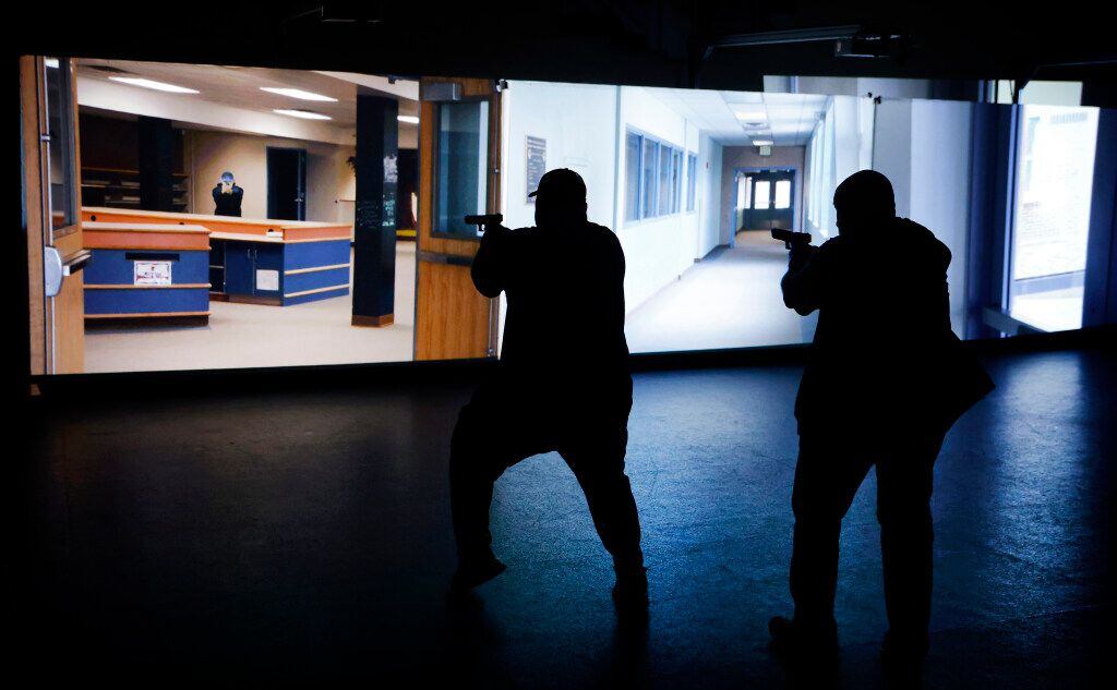 A pair of school district employees respond to a video simulation of an active shooter...