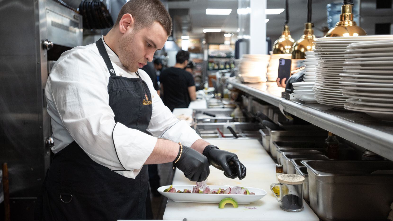 El chef Rodrigo Lomelí le da los toques finales a un platillo en la cocina del restaurante...