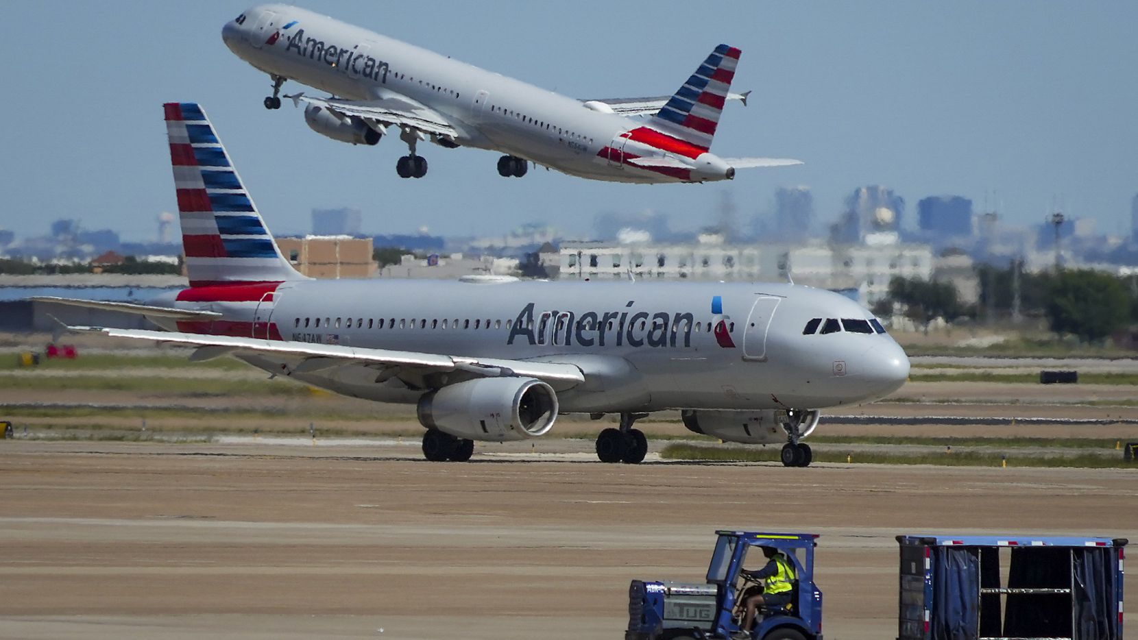 An American Airlines planes takes off as another taxis toward Terminal C at DFW Airport on...