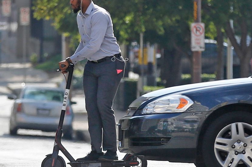 A man on a scooter crosses an intersection in downtown Dallas this month.