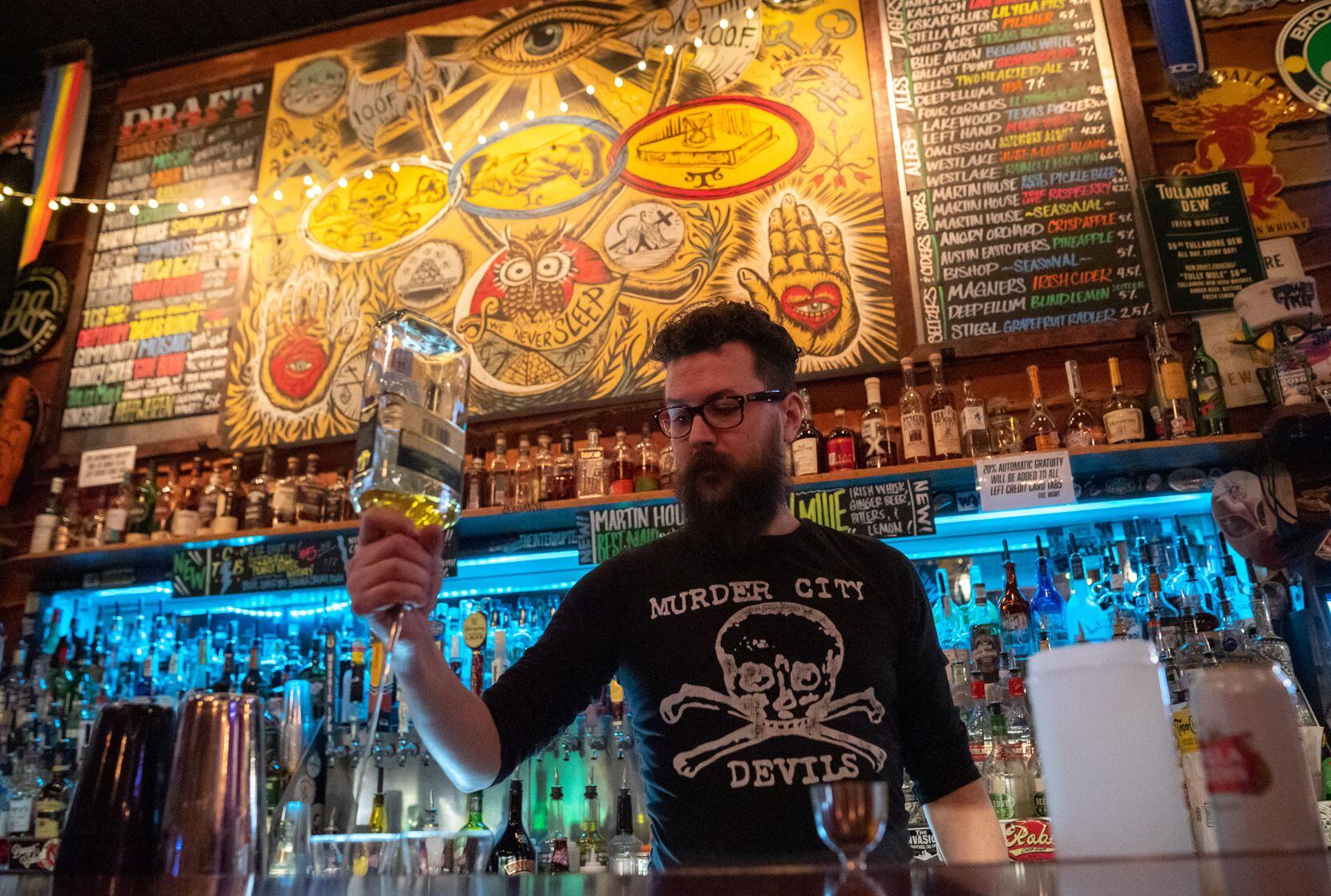 Bartender Evan Johnson, 38, pours liquor into shot glasses while working a shift at Three...