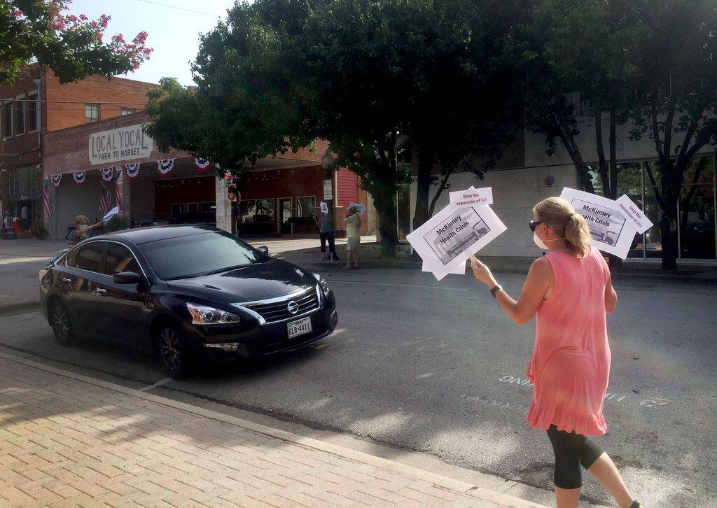 A McKinney resident holds signs with the words "McKinney Health Crisis" in protest of a proposal to expand the Martin Marietta concrete batch plant. (Nanette Light/Staff)