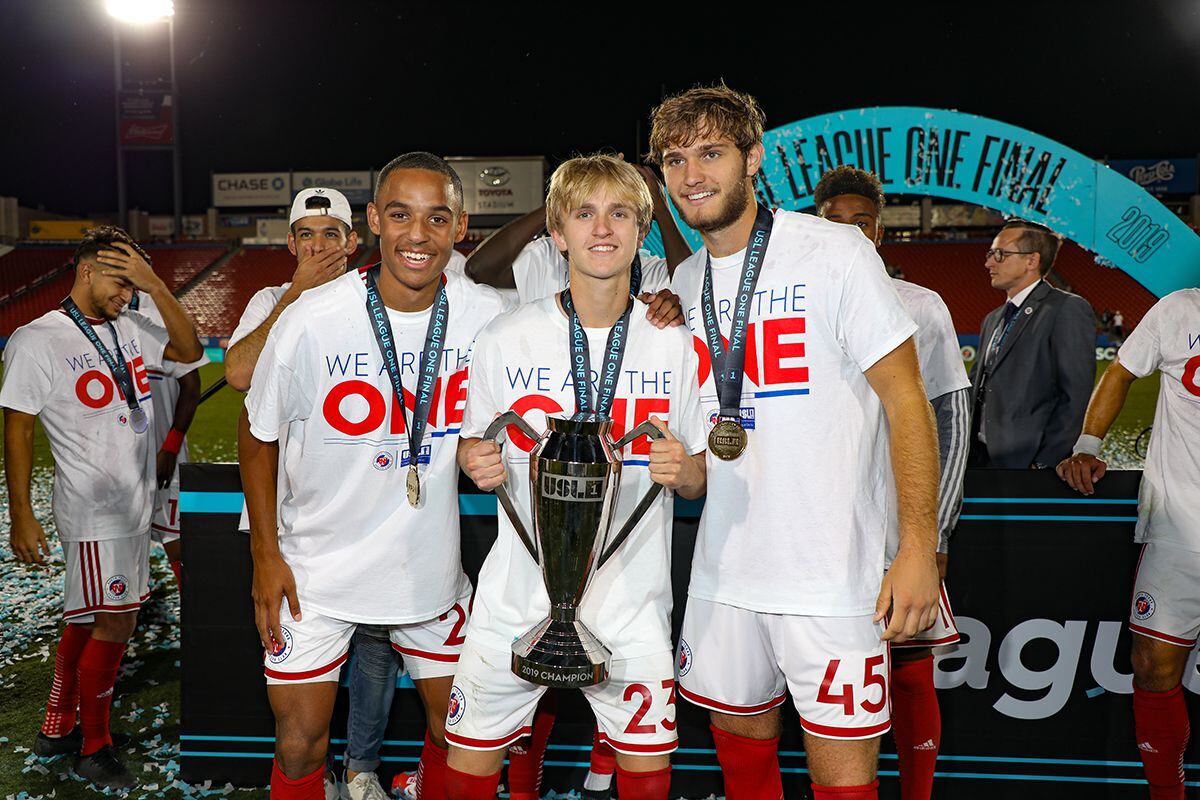 Bryan Reynolds (left), Thomas Roberts, and Tanner Tessmann (right) celebrate with the USL-1...