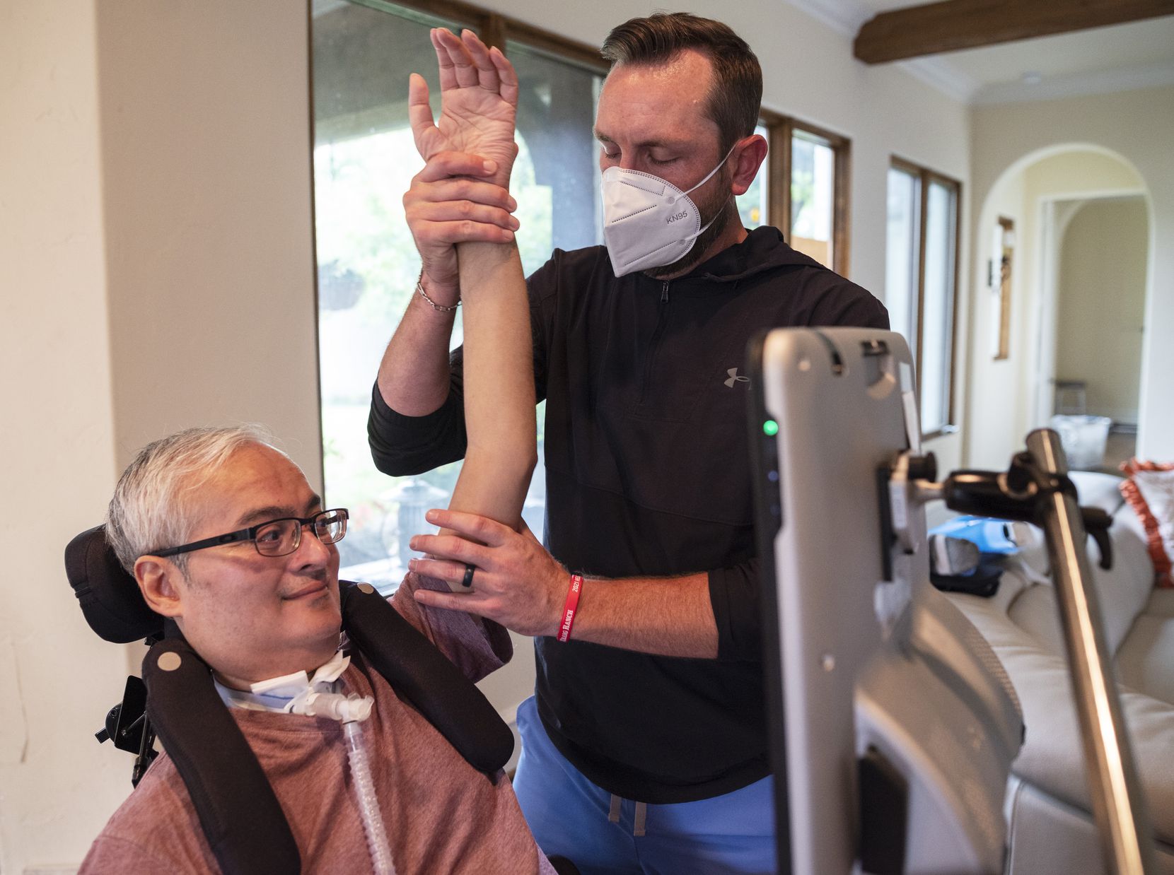 Resilient Healthcare vice president of operations and physical therapist Brian Chace works with patient Raghav Gupta on stretching his arms as part of his at home care on June 28 at Gupta's home in Dallas.