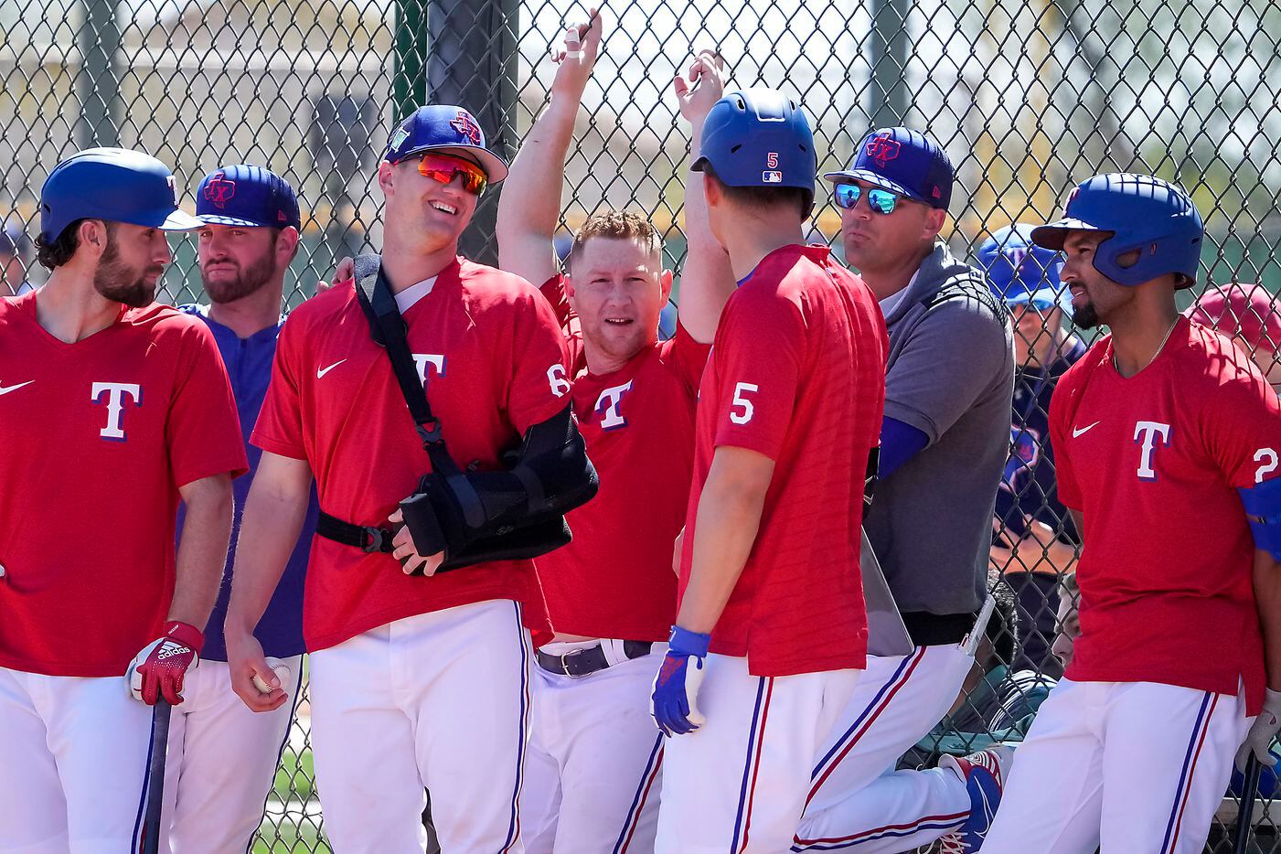 Texas Rangers infielder Josh Jung (center) wears a sling as laughs with teammates (in red,...