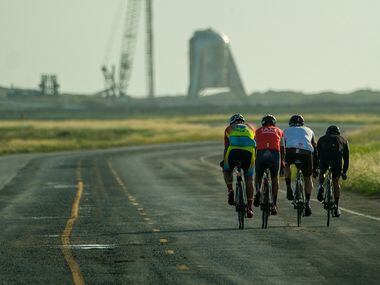 A group of cyclist ride on Boca Chica Boulevard toward the Starhopper spaceraft at the...