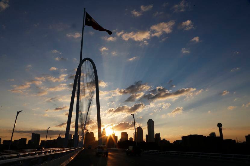 The sun emerges over the Dallas skyline with the Margaret Hunt Hill Bridge  in the...