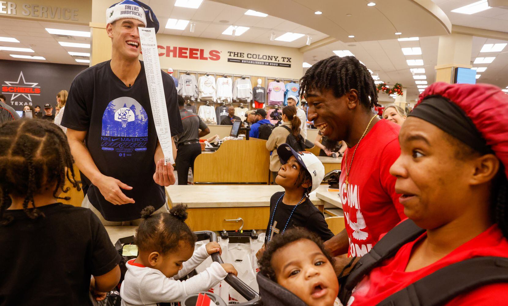 Dallas Mavericks center Dwight Powell (center) shows the Givens family a receipt from their...