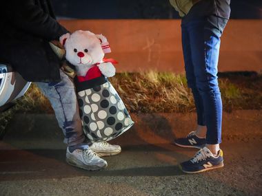 A man experiencing homelessness holds a teddy bear that he was carrying as he stops to...