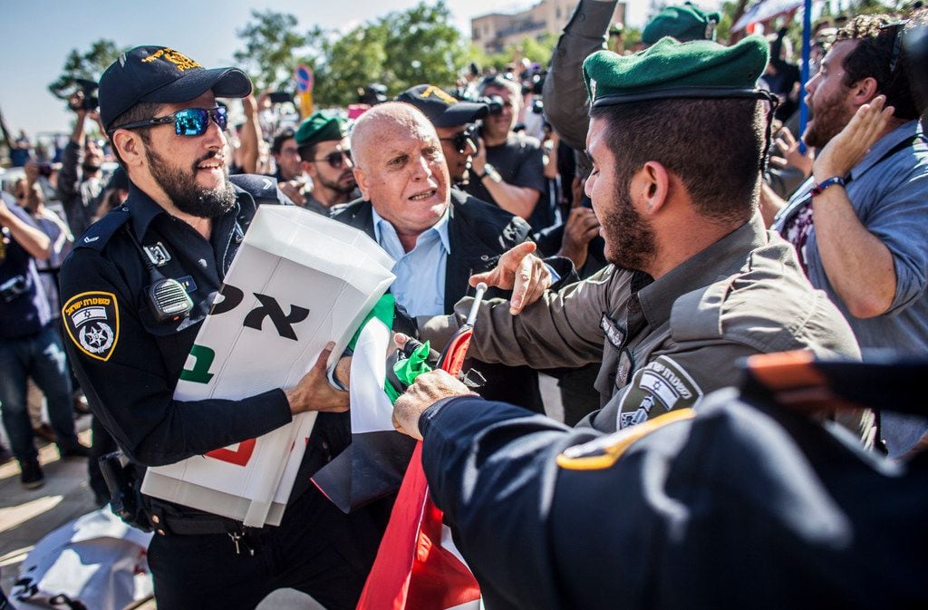 Israeli border police officer pulls a sign from a Palestinian protestor outside the new U.S....