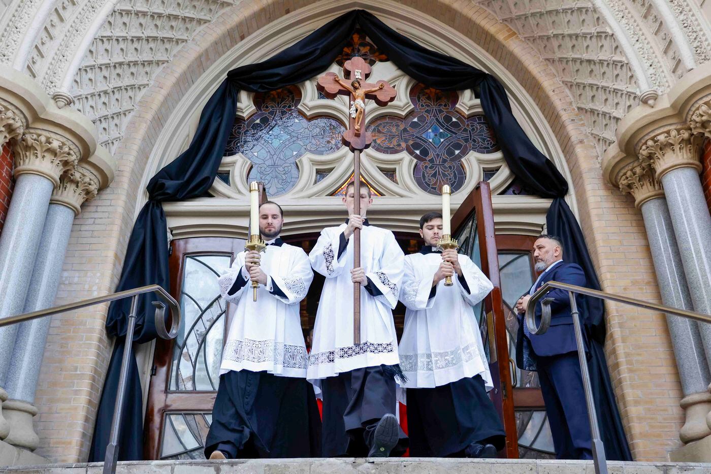 Seminarians process out of the church’s main entrance draped by black bunting symbolizing...