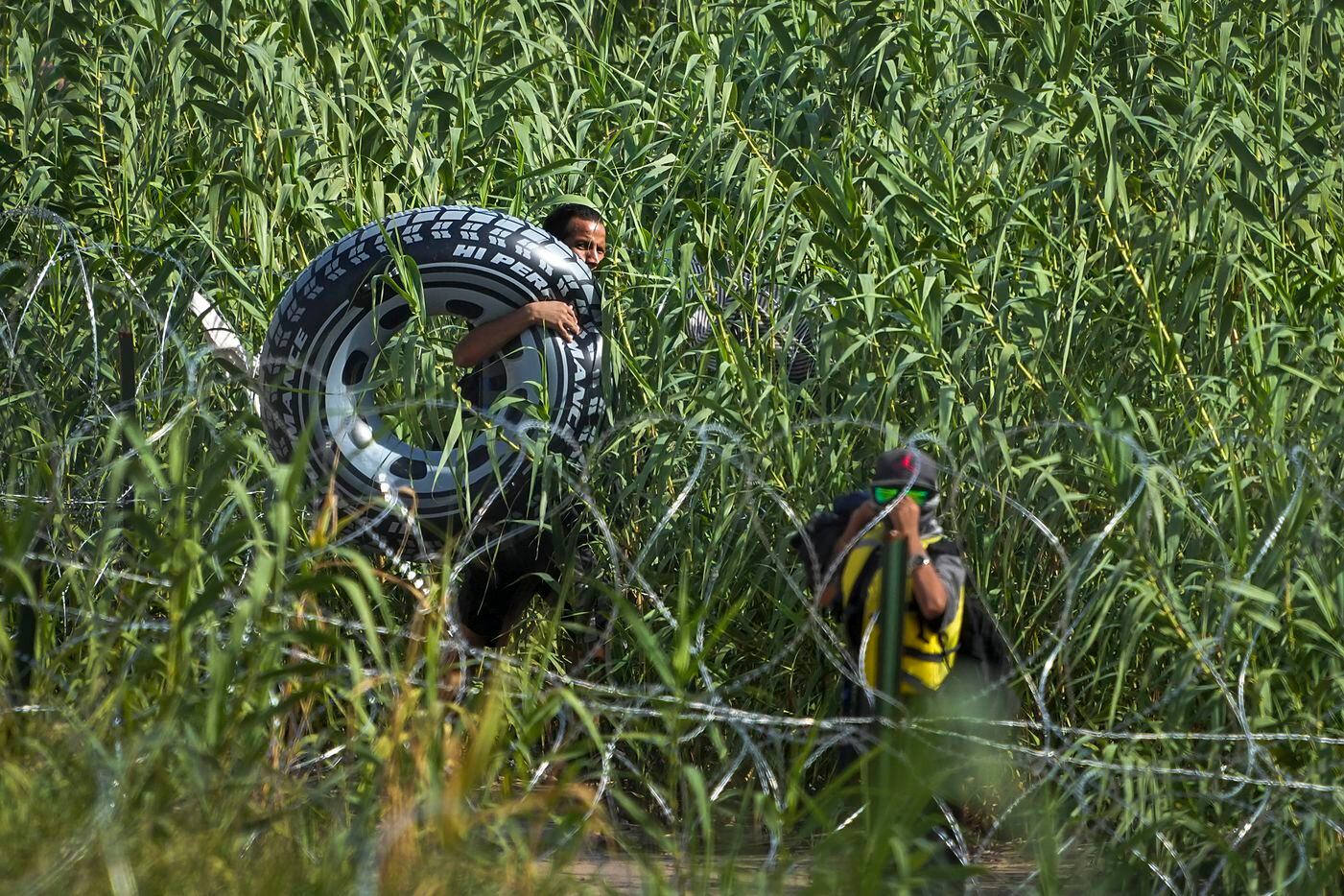 A man carrying a floatation device disappears into foliage on the banks of the Rio Grande on...