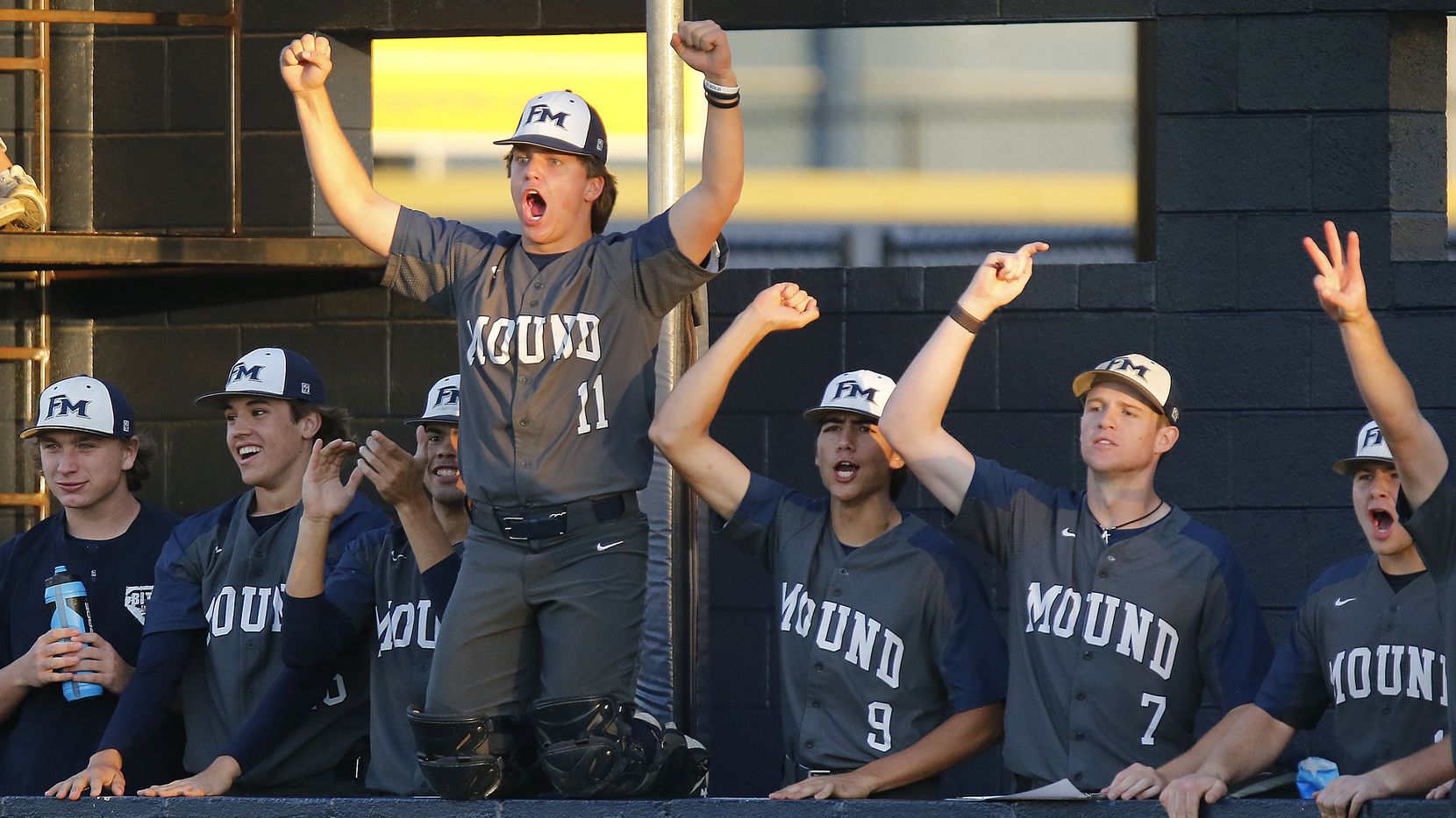 The Flower Mound High School dugout celebrates runners loading the bases in the second...