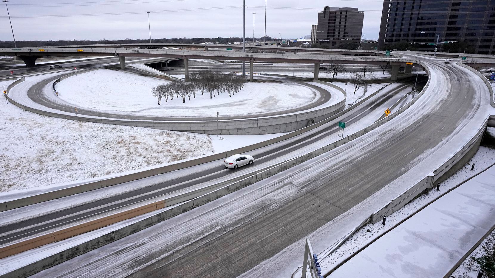 A lone driver makes their way through icy road conditions at the LBJ 635 Freeway and North...