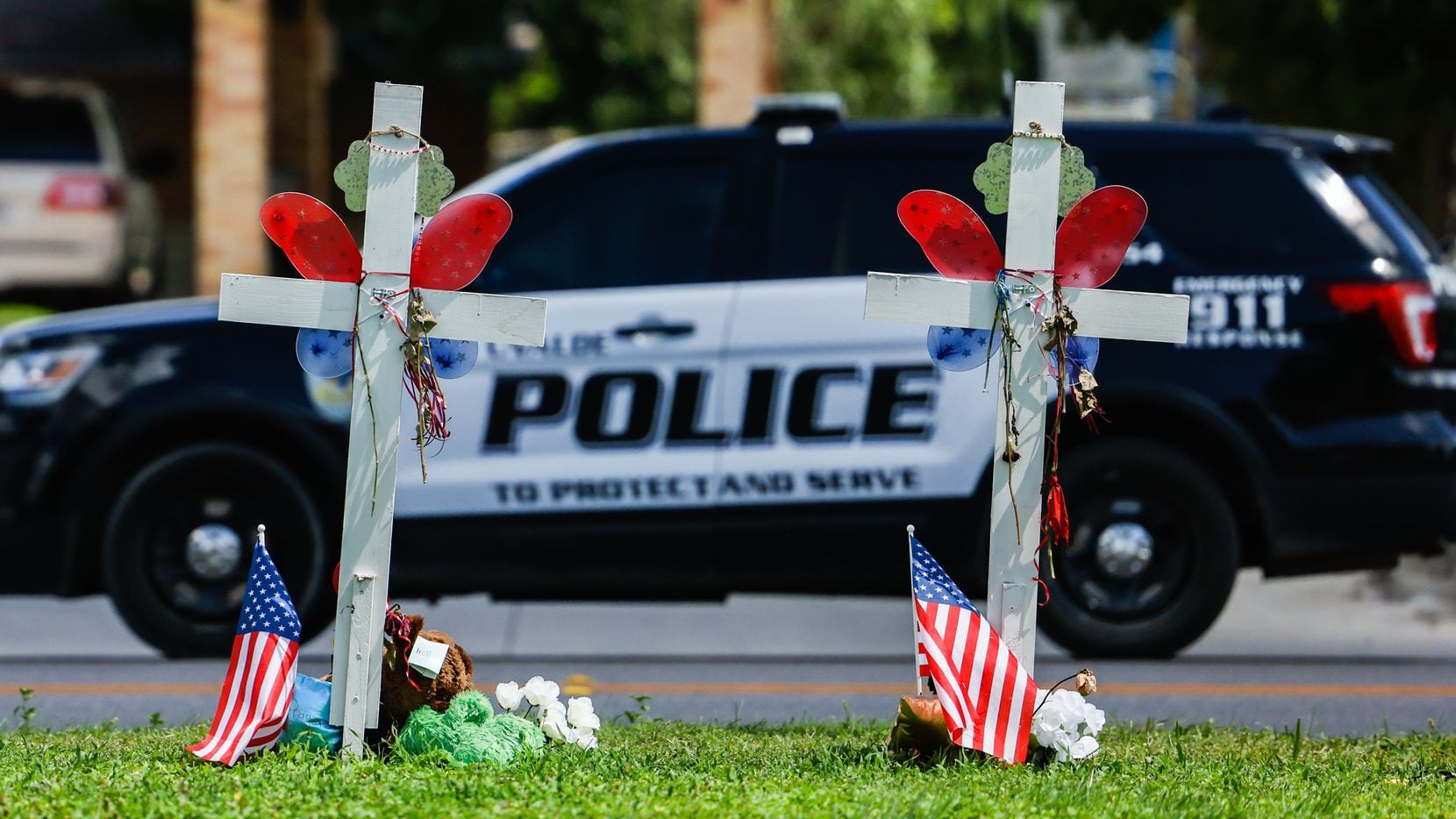 A Uvalde police SUV passes by a memorial in honor of the 21 victims of a mass shooting at...