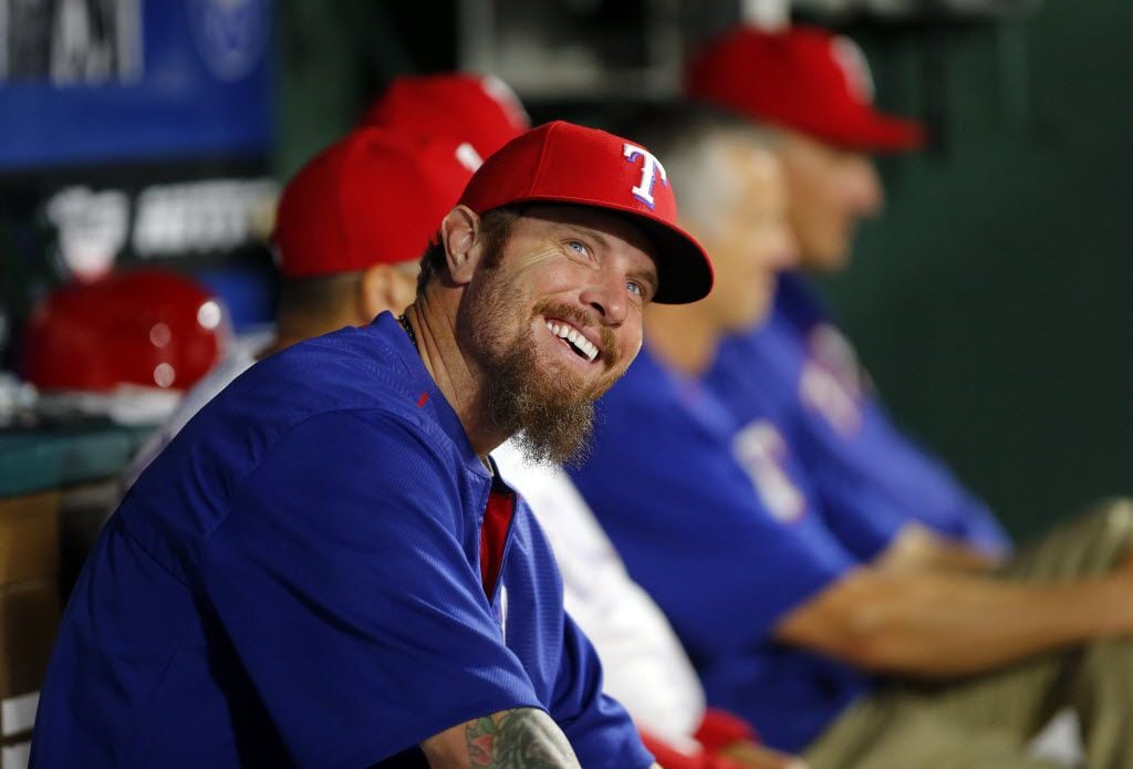 Texas Rangers Josh Hamilton smiles from the bench while talking to coaches  in the dugout...