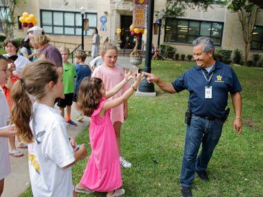 Jesus Gonzalez, a janitor for University Park Elementary School, is greeted by Anna Bel, 6,...