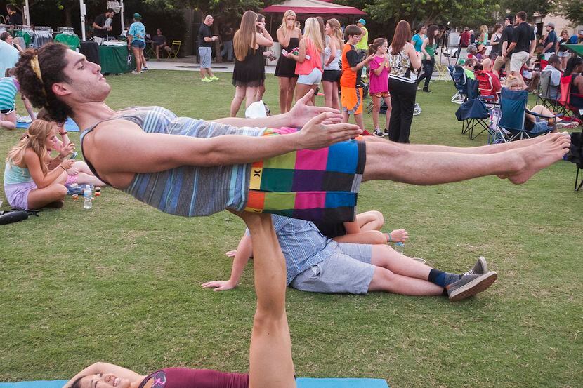 A couple performs acro yoga in a park.