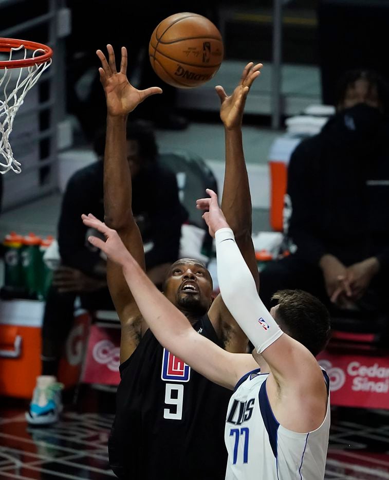 LA Clippers center Serge Ibaka (9) grabs a rebound from Dallas Mavericks guard Luka Doncic (77) during the first half of an NBA playoff basketball game at Staples Center on Tuesday, May 25, 2021, in Los Angeles.