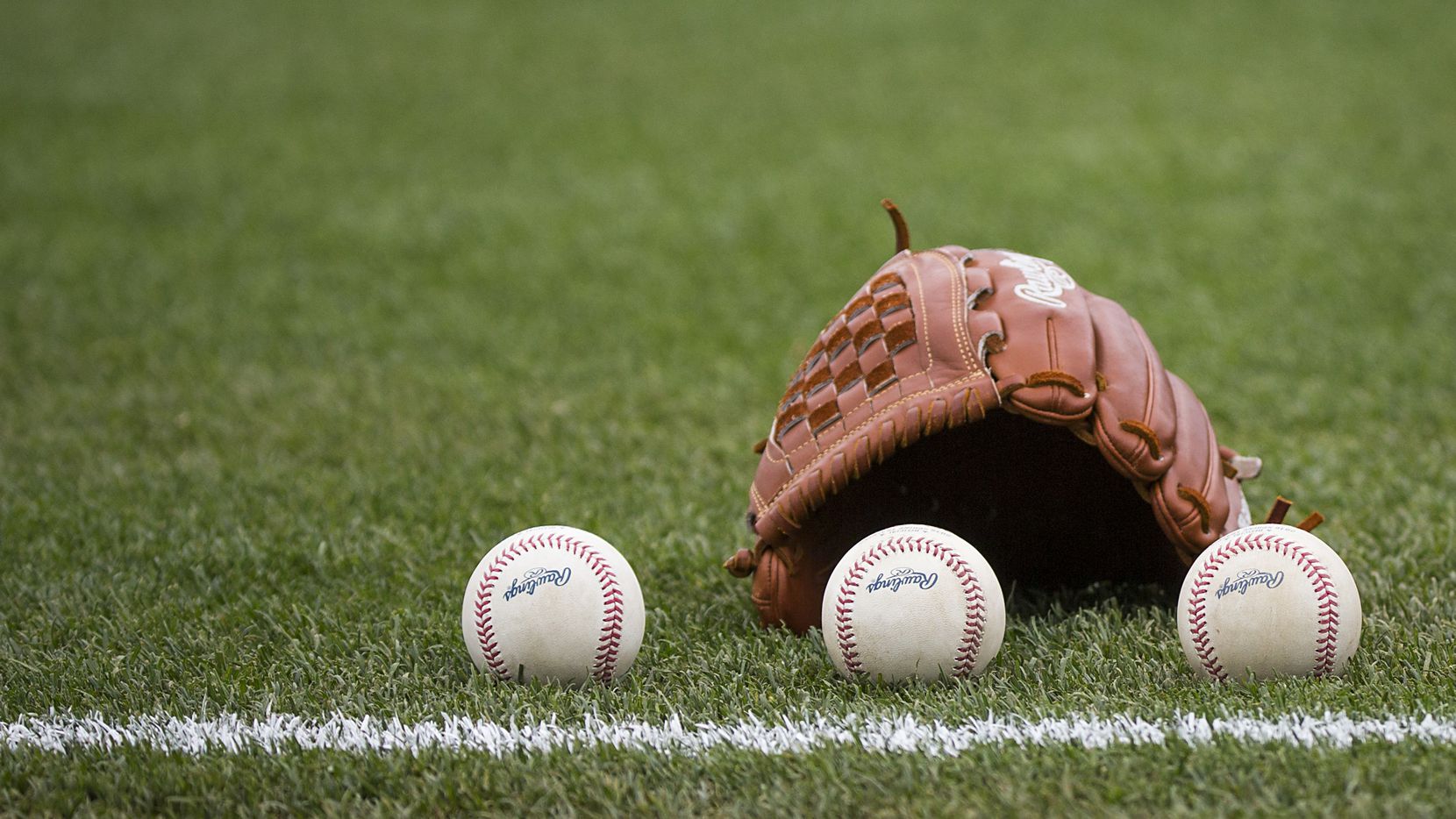 Balls rest next to the glove before a Texas Rangers spring training game against the Seattle...