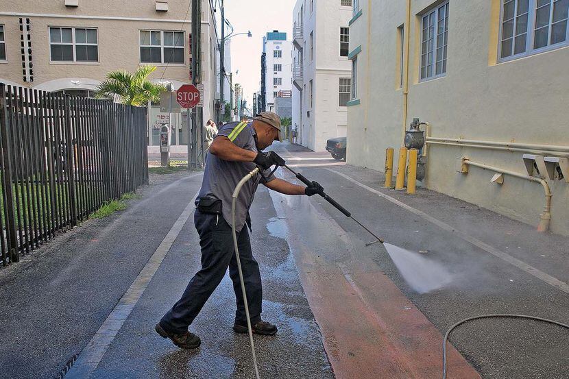 Melvin Gaitán, del Departamento de Salubridad de Miami Beach, limpia un callejón con agua a...