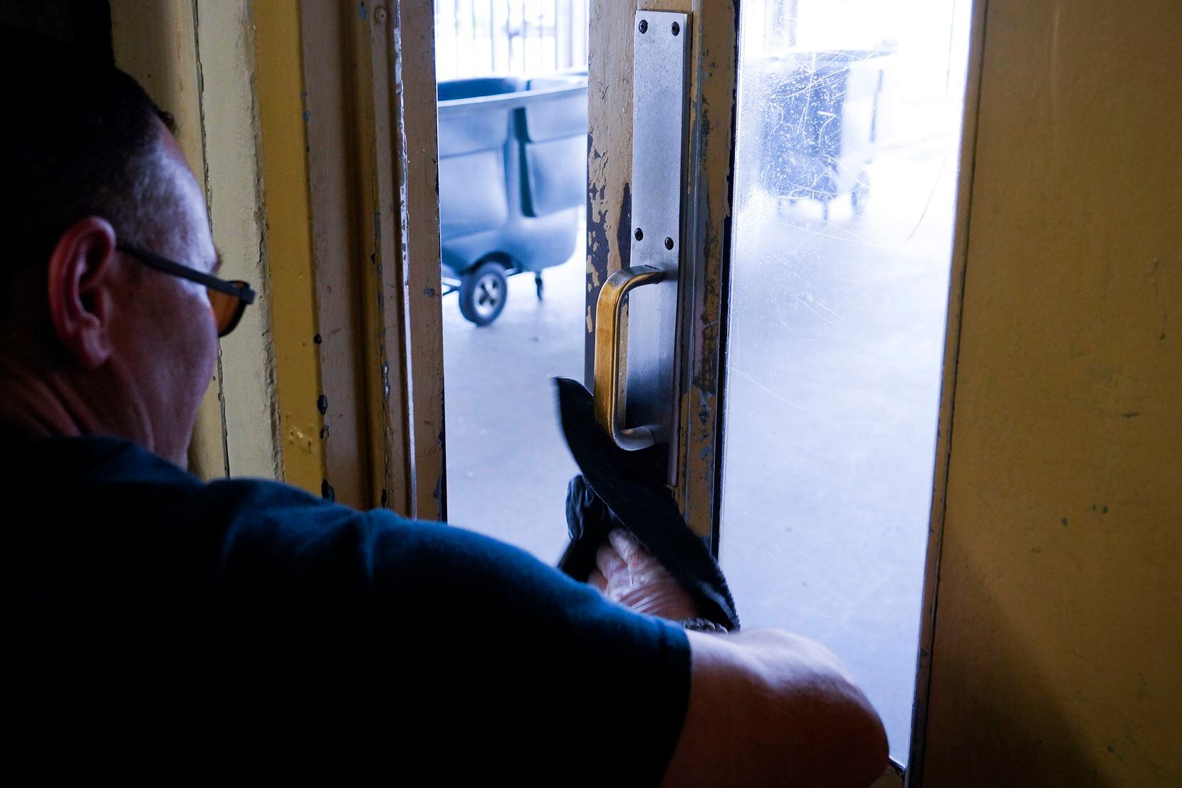Clayton Carr wipes down door handles with disinfectant at Austin Street Center on Wednesday,...