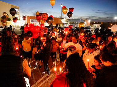 People bow their heads during a prayer before releasing balloons in memory of 11-year-old...