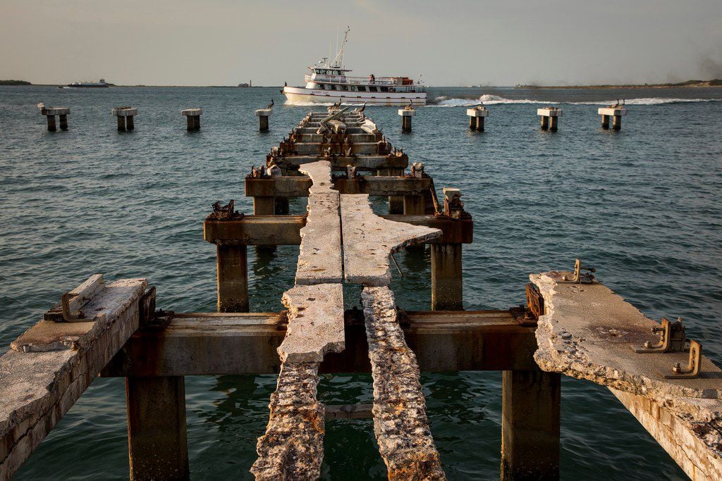 The Wharf Cat charter fishing boat passes the remains of a pier destroyed by Hurricane...