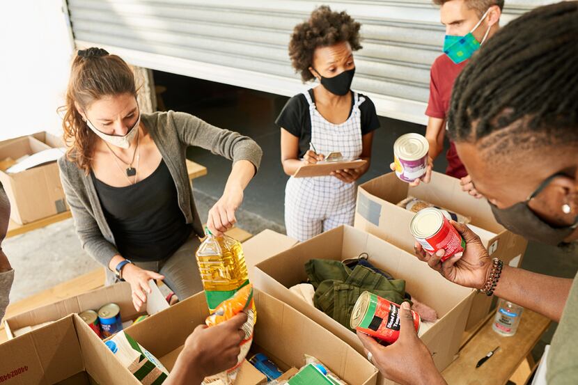 Teens wearing masks place canned foods and other necessities in cardboard boxes