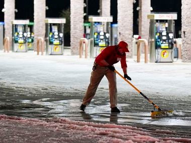 Employee Christopher Scroggins clears snow and ice from walkways in the parking lot at...