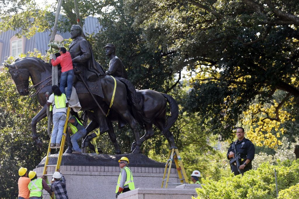 Workers prepare for the removal of a statue of Robert E. Lee at a public park in Dallas,...