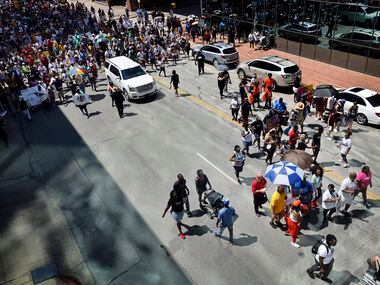 A large group of supporters follow Opal Lee (under umbrellas, right) down Commerce St....