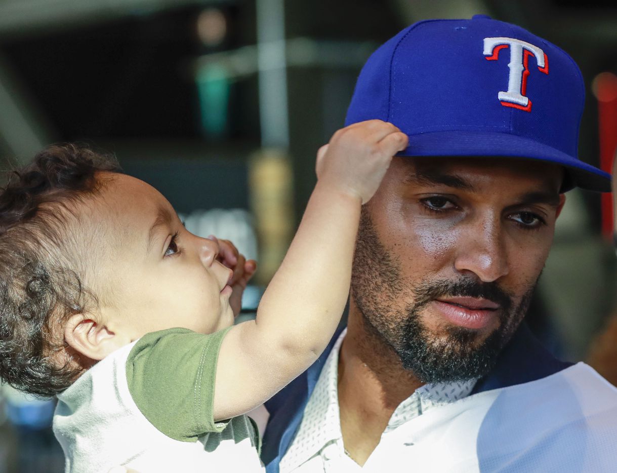 Marcus Semien holds his child at a news conference at Globe Life Park in Arlington on Wednesday, Dec. 1, 2021. Former Toronto Blue Jays, Marcus Semien, signed a contract with the Texas Rangers for 175 million dollars. (Rebecca Slezak/The Dallas Morning News)