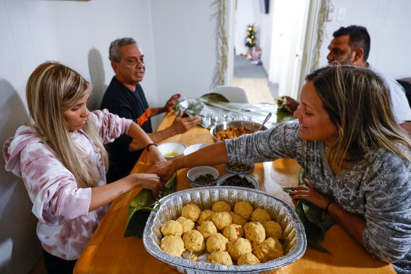 Sue Chacin, a la izquierda, envuelve una hoja de plátano con estofado de carne mientras su...