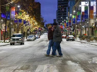 Shane Yeager (left) and Owen Powell cross Main Street at Akard Stree in downtown Dallas on...