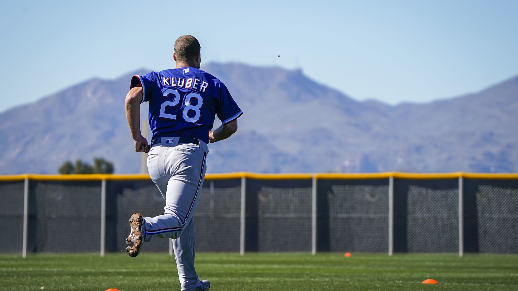 Texas Rangers pitcher Corey Kluber runs on a conditioning field during a spring training...