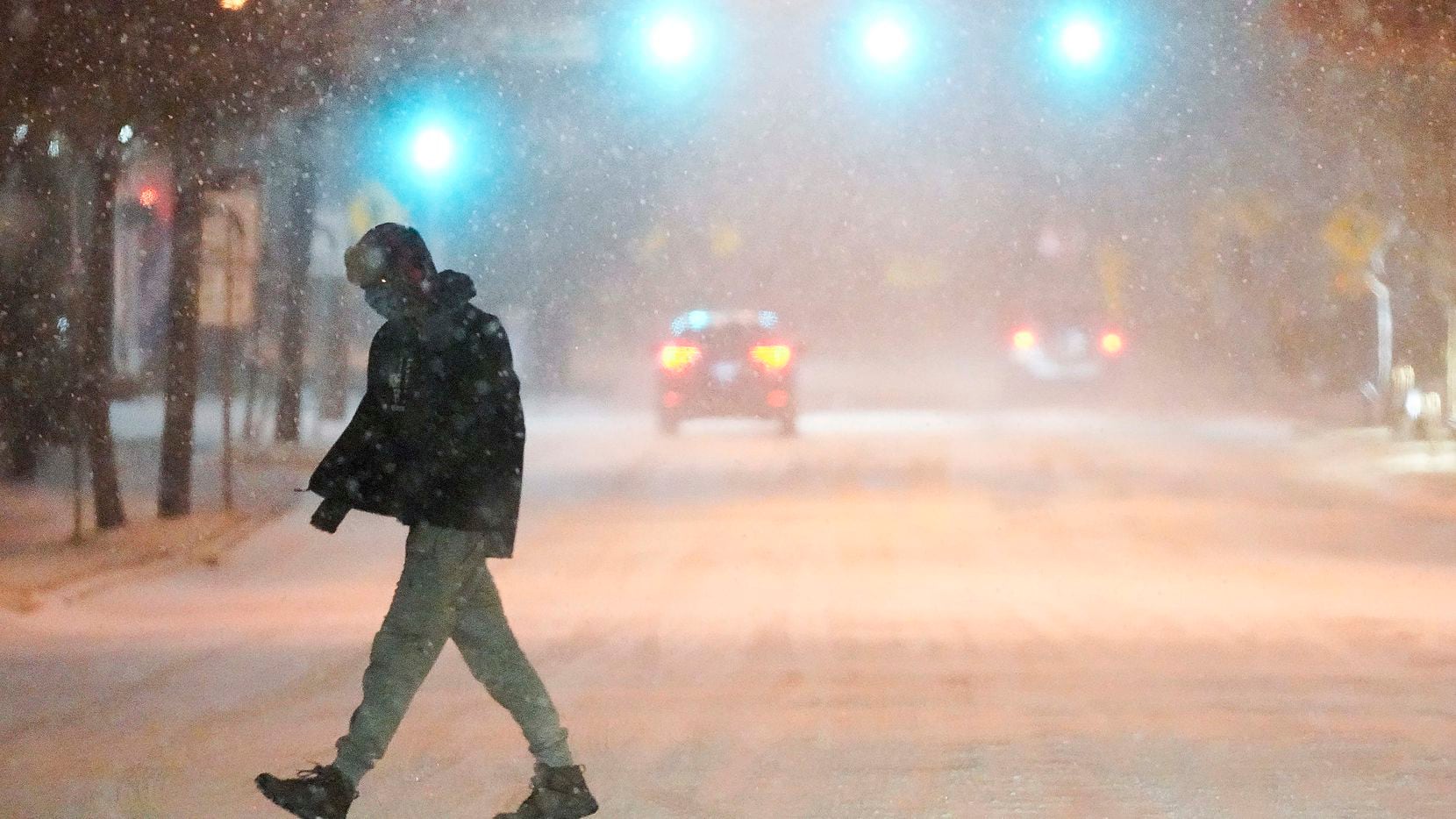 A man crosses the street as a winter storm brings snow and freezing temperatures to North...