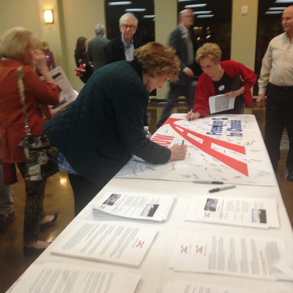 Residents sign a banner to be sent to transportation officials in Austin during the LBJ East...