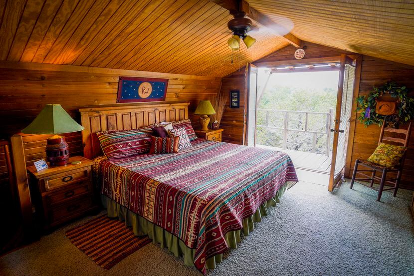 A view to the deck and woods outside the bedroom of the two-story Cedar House at Paluxy...