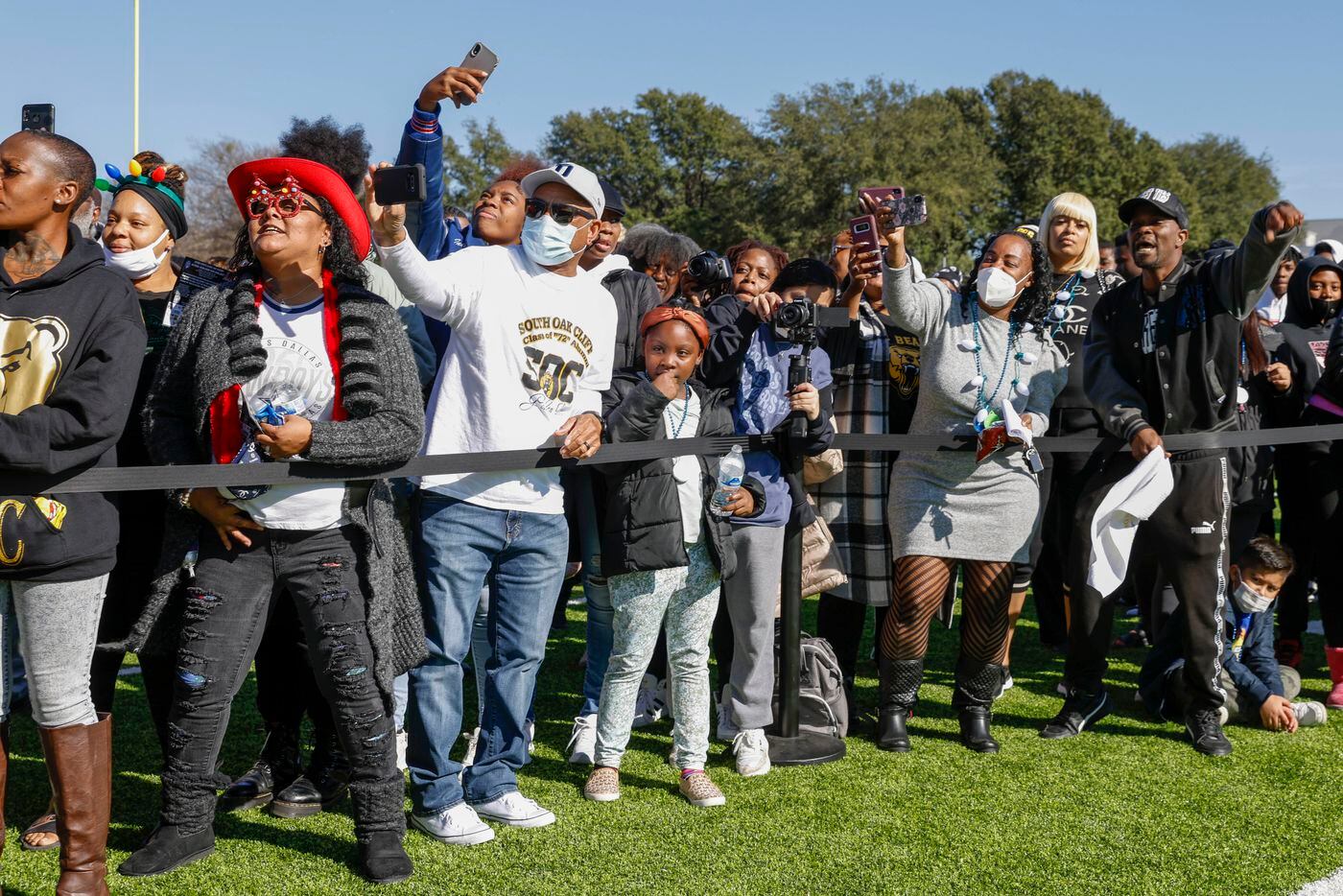 Community members and fans of South Oak Cliff take photos and cheer as the team appears...