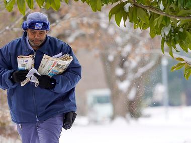 USPS mail carrier RayShawn Riley delivers mail to a snow covered neighborhood after a second...