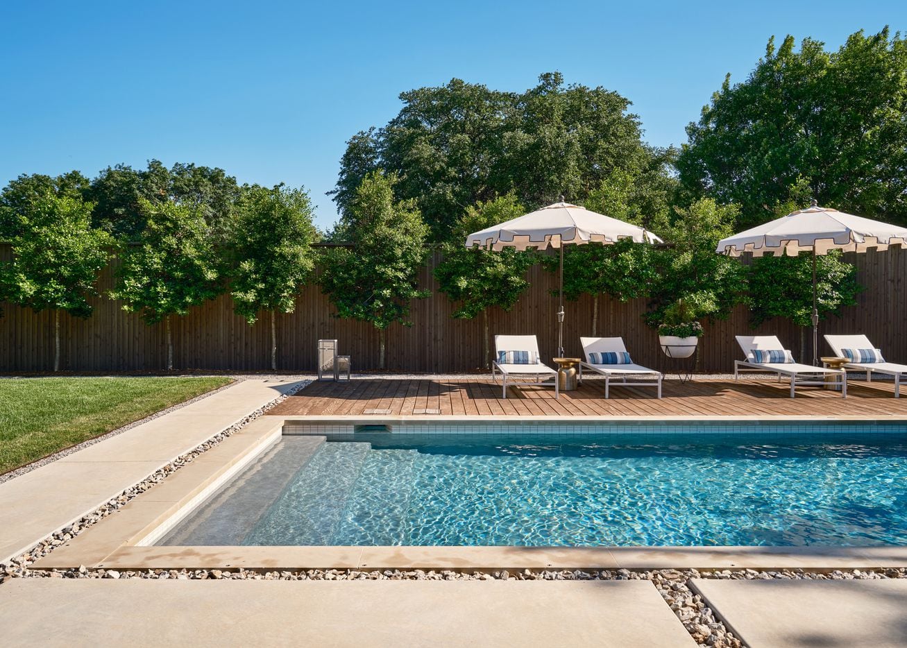 The backyard pool features loungers and umbrellas in a Palm Beach style.