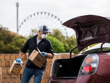 Volunteer Joe Skenderian places boxes of food in the back of a vehicle.