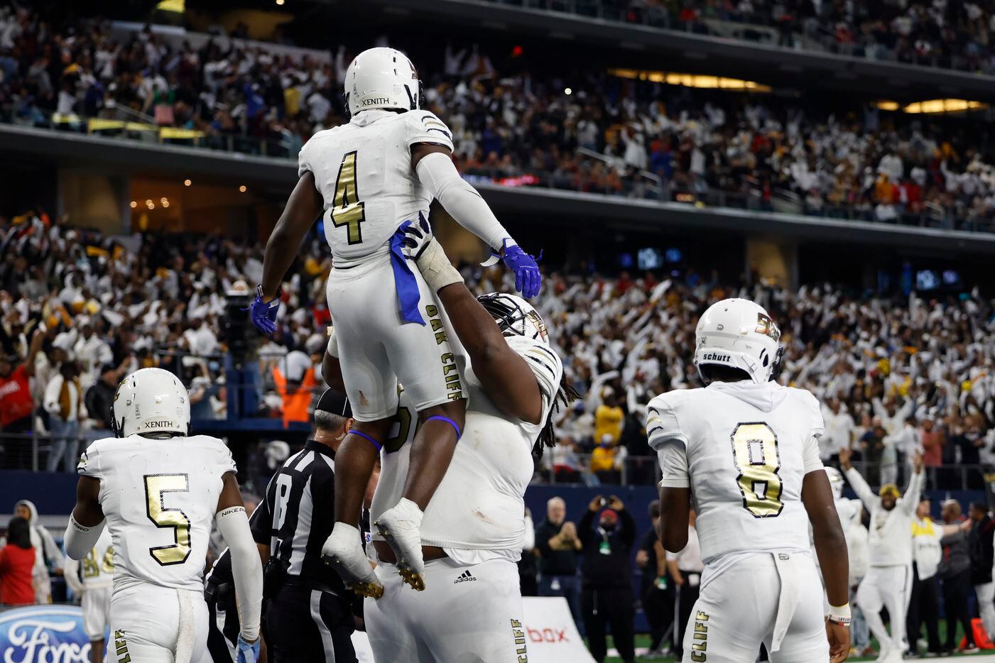 South Oak Cliff offensive lineman Brione Ramsey-Brooks (58) lifts South Oak Cliff running back Qualon Farrar (4) into the air after Farrar scored a touchdown during the fourth quarter of their Class 5A Division II state championship game against Liberty Hill at AT&T Stadium in Arlington, Saturday, Dec. 18, 2021. South Oak Cliff defeated Liberty Hill 23-14 for Dallas ISD’s first title since 1958. (Elias Valverde II/The Dallas Morning News)