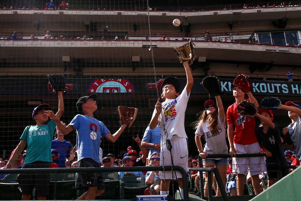 Young Texas Rangers fans catch a ball during a MLB game between Texas Rangers and New York...