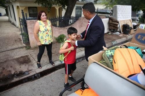 Adán González platica con Carmen Bueno mientras le entrega a su hijo una mochila llena de...