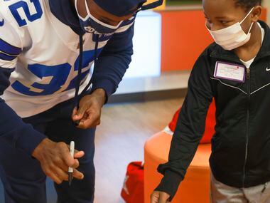 Blaze Anderson looks at Dallas Cowboys cornerback Kendall Sheffield (32) after he autographs...