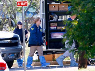 FBI investigators get dressed in protective suits as they work a crime scene where the body...